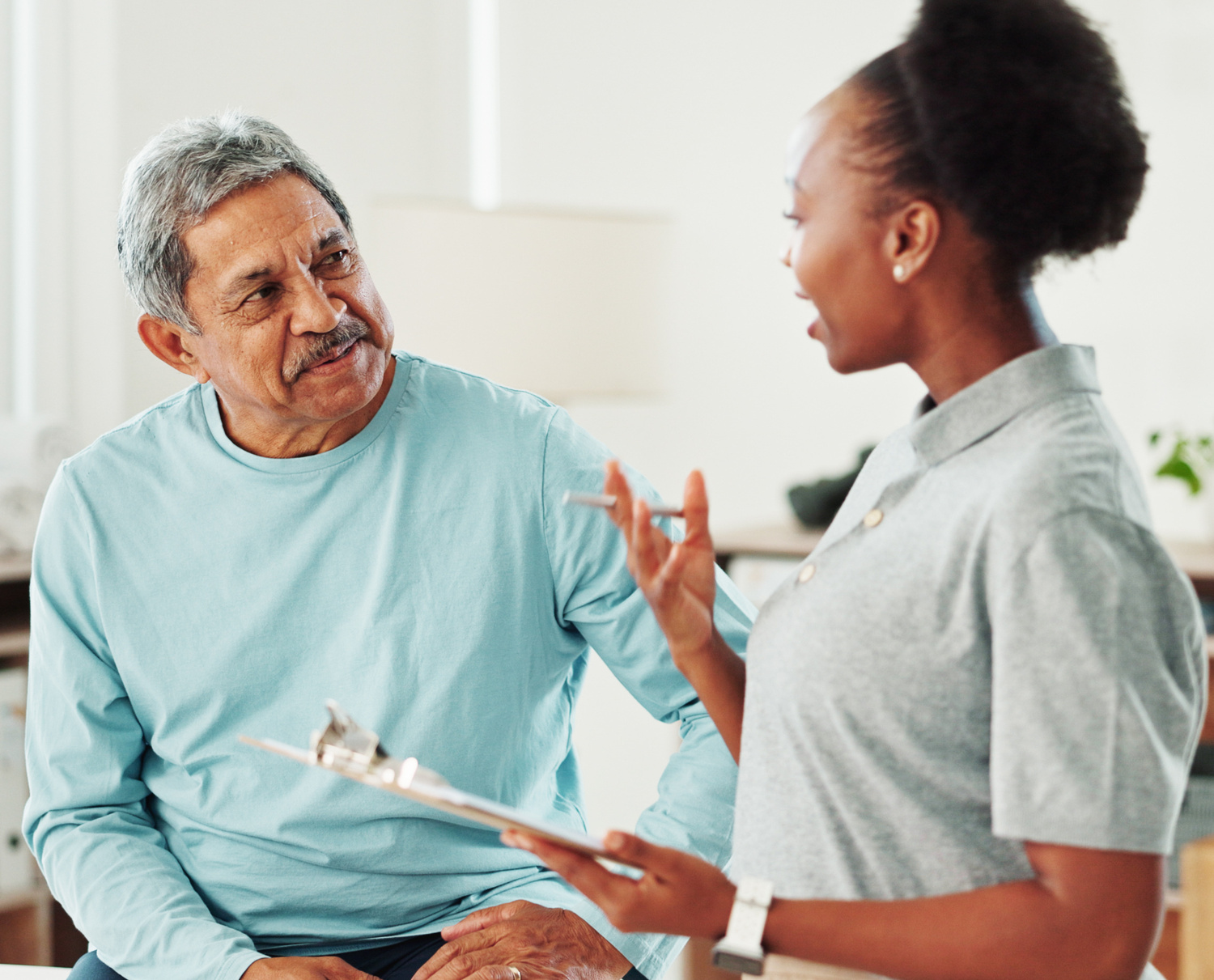 Physiotherapist, woman and senior man with checklist, discussion and questions at clinic. People, clipboard and report for injury with talking, advice and medical assessment for wellness at hospital